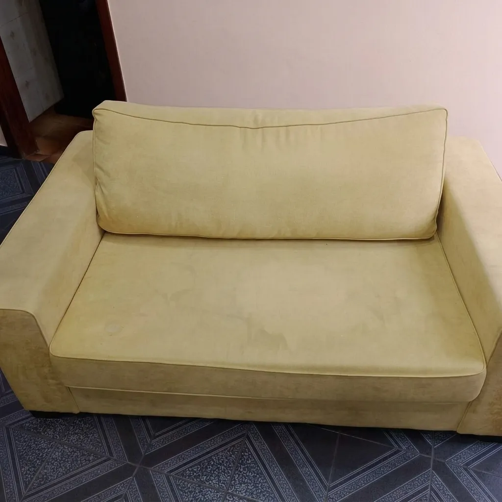 Sofá amarelo antes da higienização, com tecido encardido e cor desgastada pelo uso