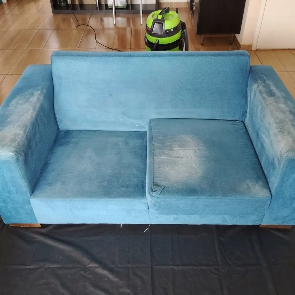 Sofá azul de 2 lugares antes da higienização, com poeira e manchas nos braços
